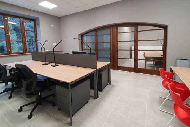 Scrivanie operative con struttura metallica nera, piano effetto rovere in ufficio moderno